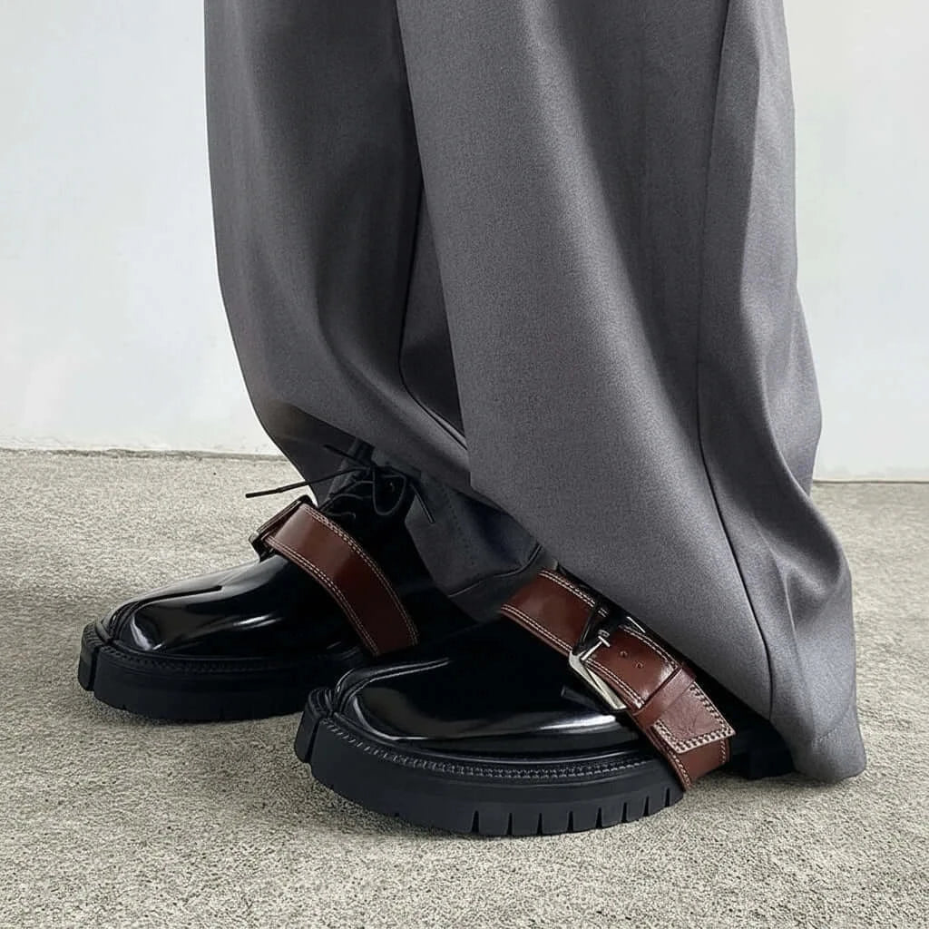 Cross Buckle Leather Tabbi Loafers styled with gray trousers on a textured floor.